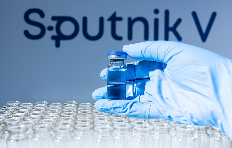 Sputnik V name in blur. Scientist holding the glass vial with Russian vaccine. 
