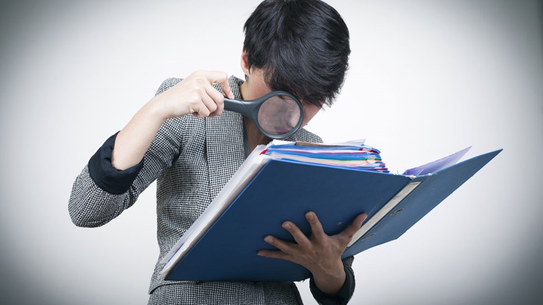 Woman with magnifying Glass Looking at Files