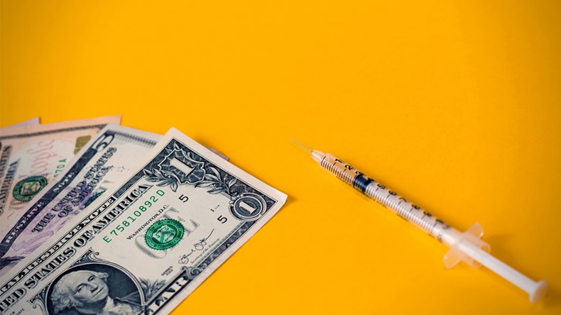 Insulin syringe and dollars money banknotes on a orange background - copy space - Image 