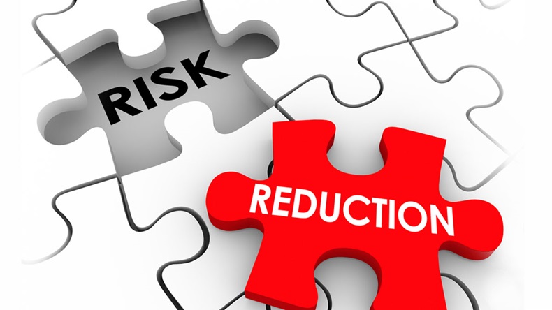 Risk Reduction words on puzzle pieces to illustrate a solution or mitigation of danger, hazard, liability or injury 