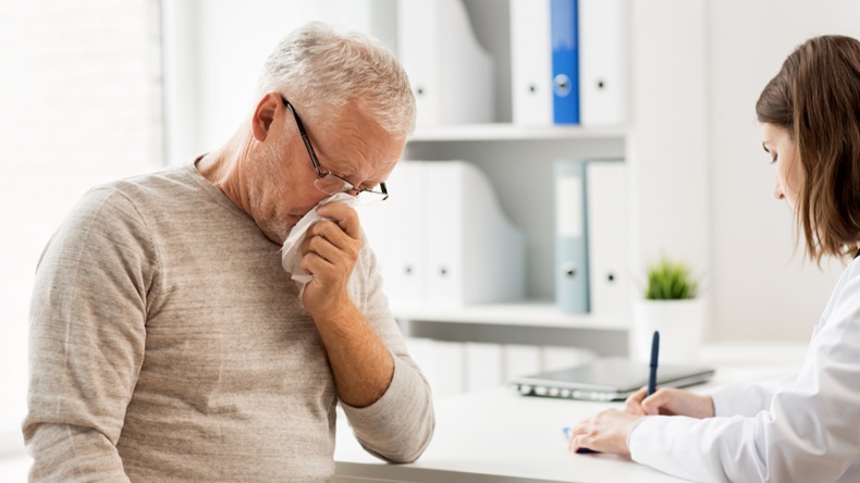 medicine, age, health care, flu and people concept - senior man blowing nose with napkin and doctor with clipboard writing at medical office at hospital - Image 