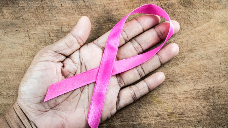 Woman holding pink ribbon on wooden background. Cancer awareness concept