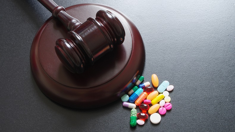 Wooden judge gavel with drugs on table
