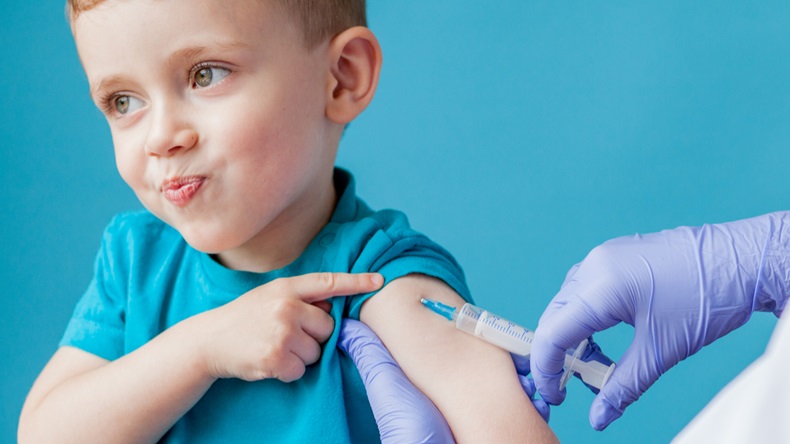 Vaccination concept. Female doctor vaccinating cute little boy on blue background, closeup.