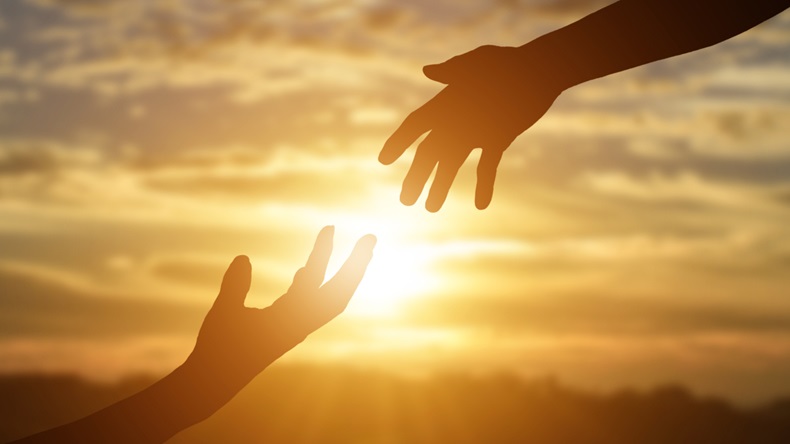 Silhouette of reaching, giving a helping hand, hope and support each other over sunset background.