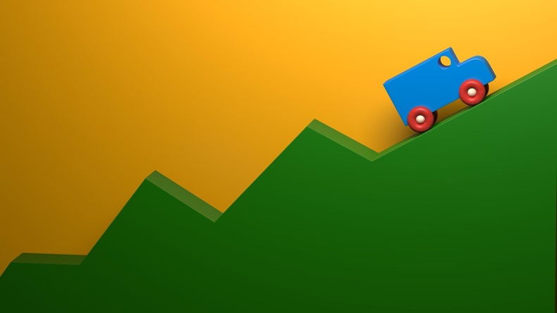 A toy truck climbing up a green hill
