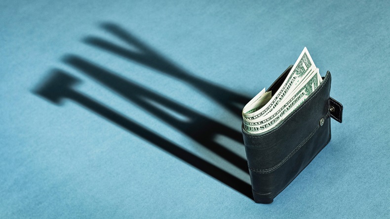 Wallet with US Dollars casting a shadow of tax, taxes or taxation