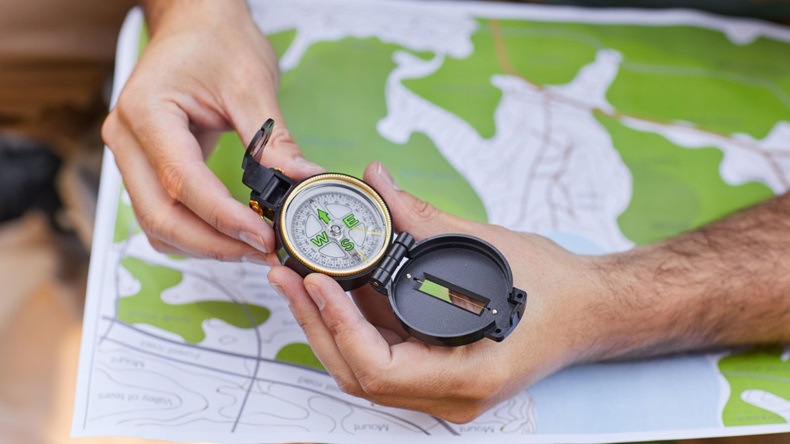 Hands holding a compass against background of a map