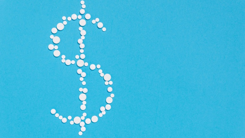 Dollar sign made out of white pills on blue background