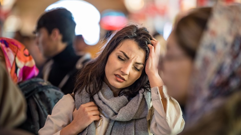 Woman suffers migraine while standing in a crowd of people