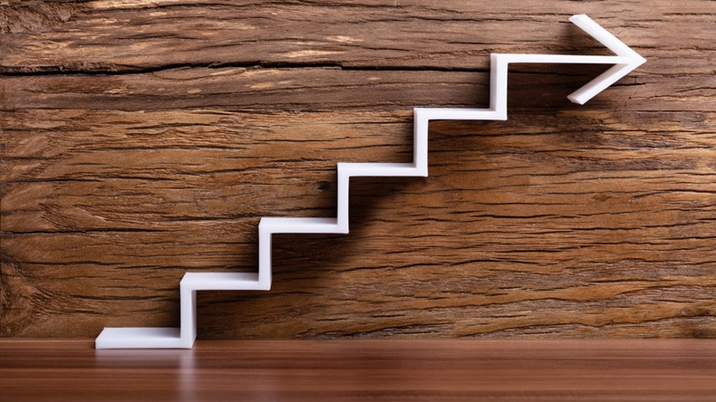 Close-up Of White Increasing Staircase Arrow On Wooden Background