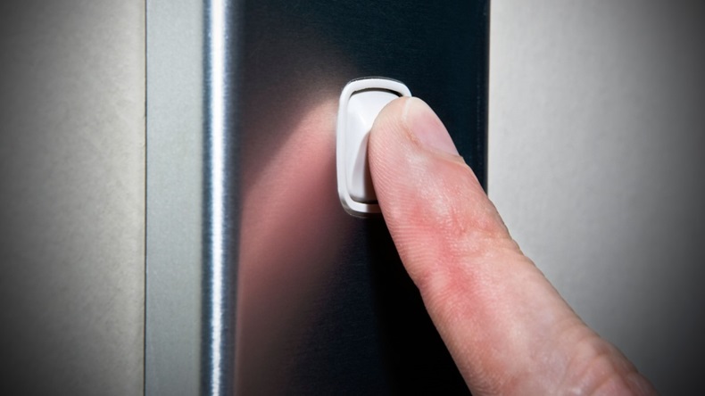 Finger pressing light switch button.