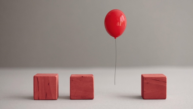 Red balloon mid air amongst wooden square cubes