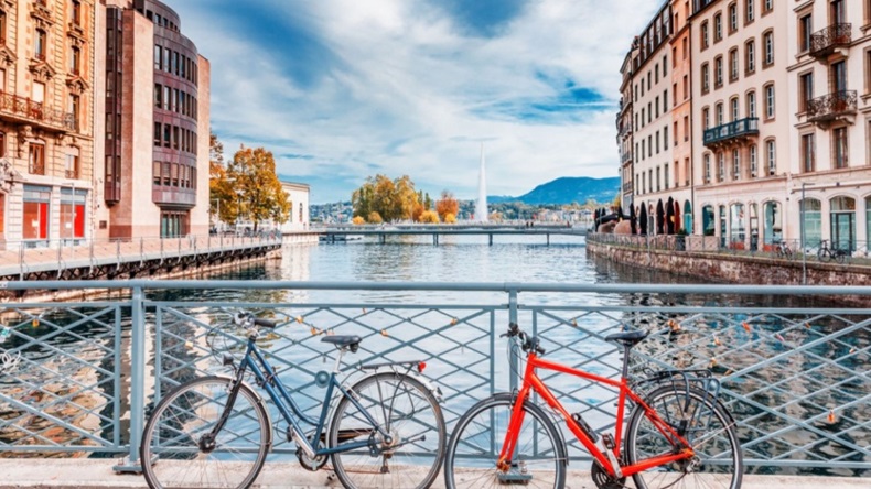 Two bicycles on a bridge in front of a lake in Geneva, Switzerland. 