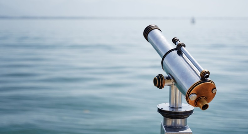 Grey telescope looking out over a body of water