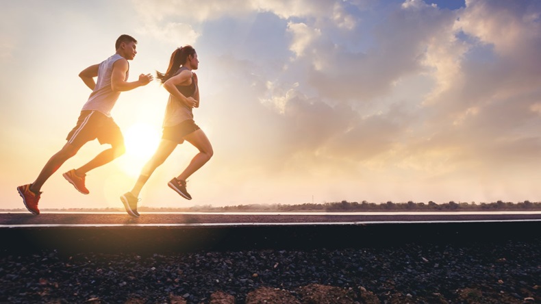 Two people running in race against sunset horizon background