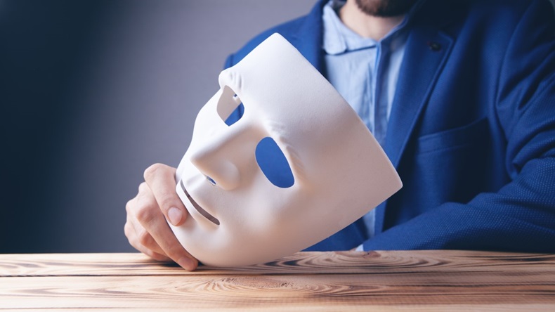 Man in blue suit holding a white mask, unmasking concept
