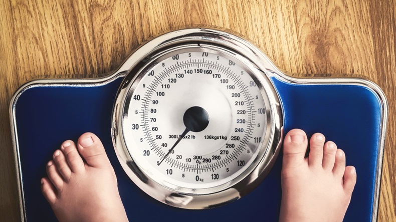 Pair of feet on blue weighing scales, obesity concept