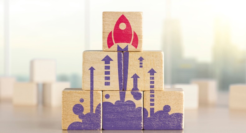 Wooden blocks with launching rocket graphic arranged in pyramid shape