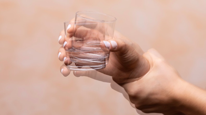 Shaking hand holding a cup, symptom of Parkinson's disease