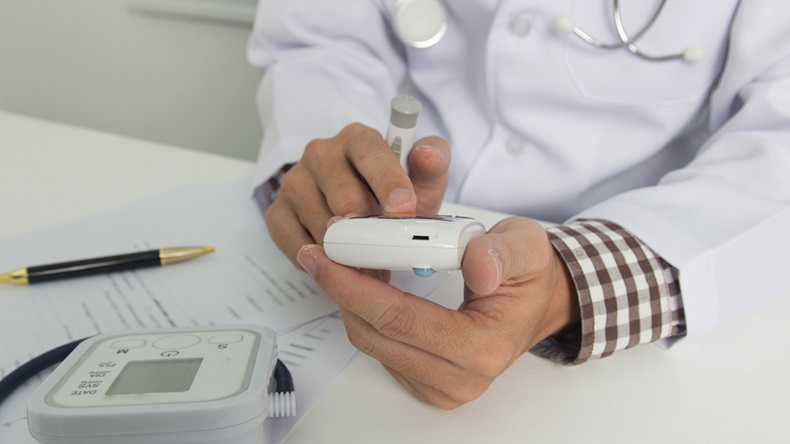 Doctor checks blood glucose monitor to meet with diabetic patients.