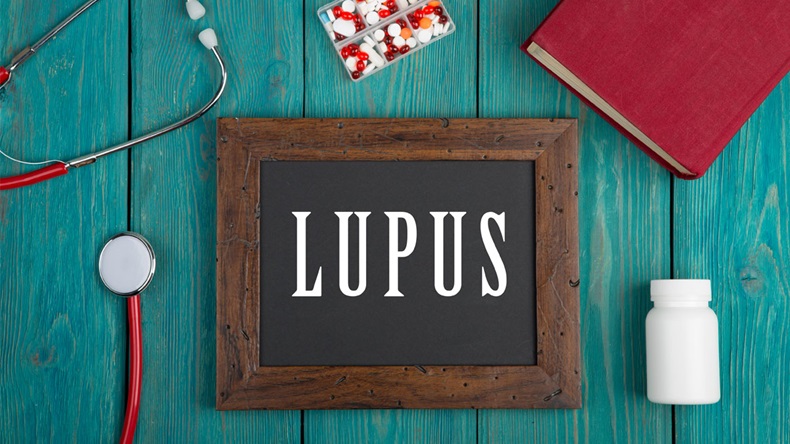 Medecine concept - Blackboard with text "Lupus", book, pills and stethoscope on blue wooden background