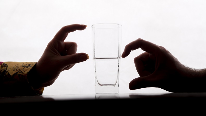 two couple are showing half full and half empty side of water glass with their fingers