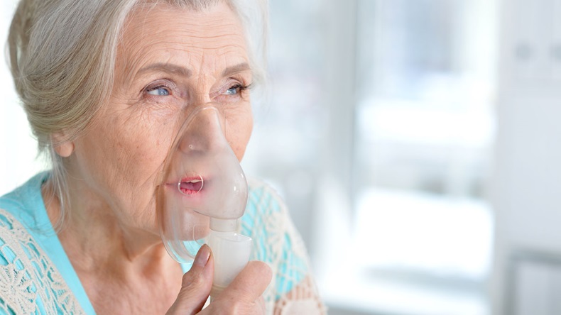 Sick elderly woman making inhalation