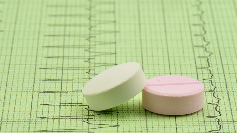 Close up of a white and a pink pills on EKG paper.