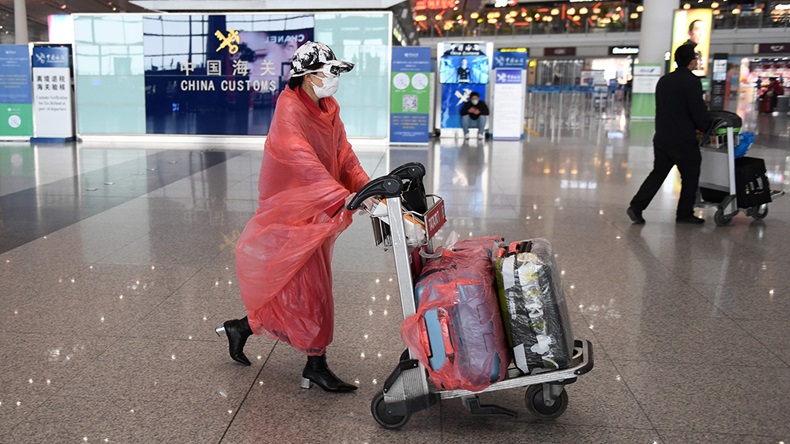 A woman wears protective clothing as a preventive measure against the COVID-19 coronavirus as she walks through Beijing Capital Airport on February 24, 2020.