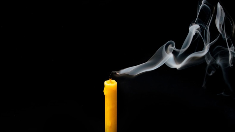 extinguished candle yellow with smoke, isolated over black
